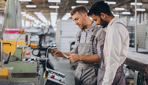 men working together near a machine in a factory.